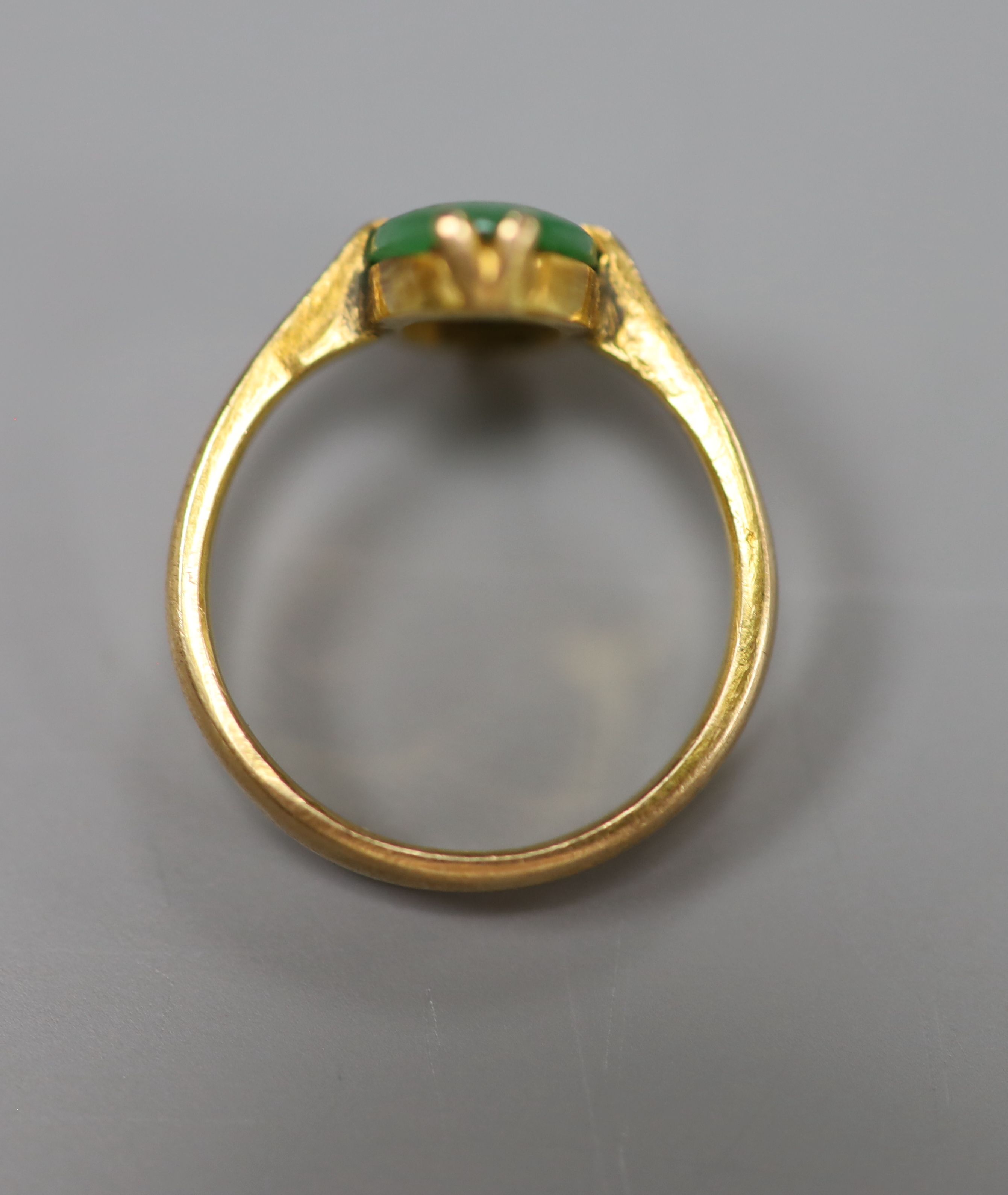 A Chinese yellow metal and oval cabochon jade set ring, size H/I, gross 3 grams.